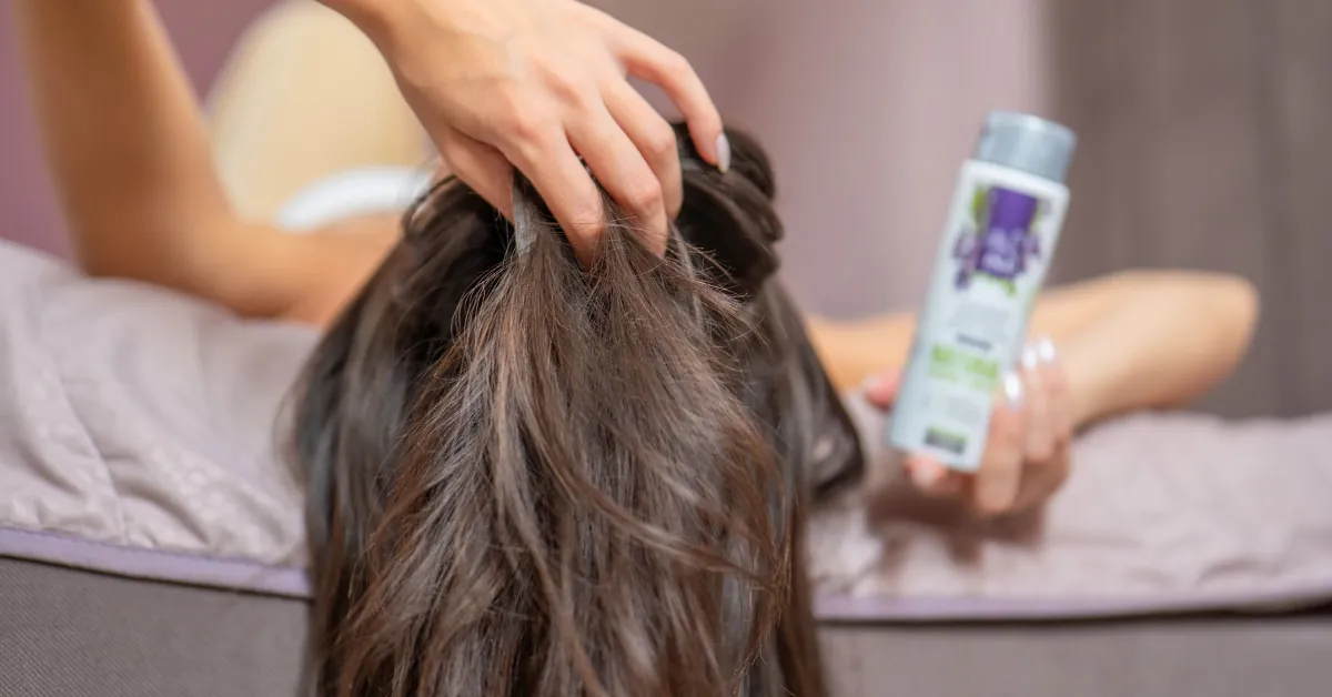 Mujer se pasa los dedos por el cabello por picor en la cabeza sin caspa, junto a ella el Agua de Salvia Orgánica Hydrolina